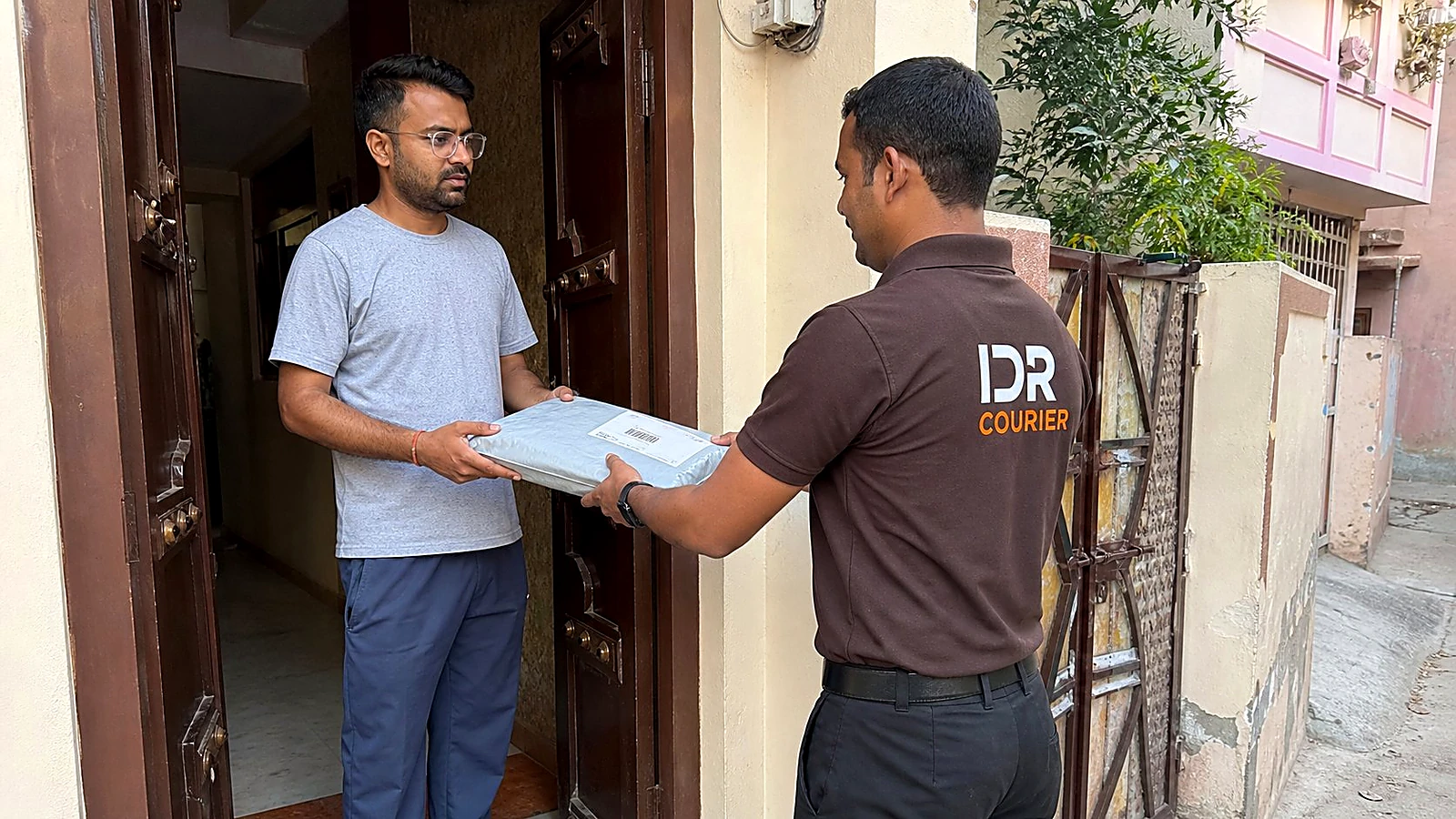 IDR Courier staff delivering a sealed parcel at a residential address in Ajmer